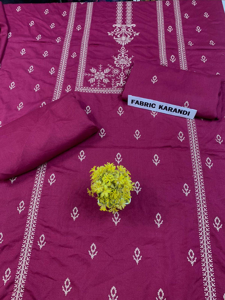 Regal Dusk Bareeze from ESHMEEN showcases beautifully intricate blue patterns on purple fabric, with two artfully folded pieces labeled as part of the Winter Collection. A small yellow bouquet is elegantly placed at the center on this premium quality fabric.