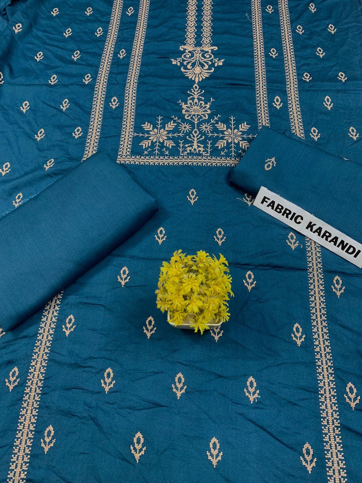 Regal Dusk Bareeze from ESHMEEN showcases beautifully intricate blue patterns on purple fabric, with two artfully folded pieces labeled as part of the Winter Collection. A small yellow bouquet is elegantly placed at the center on this premium quality fabric.