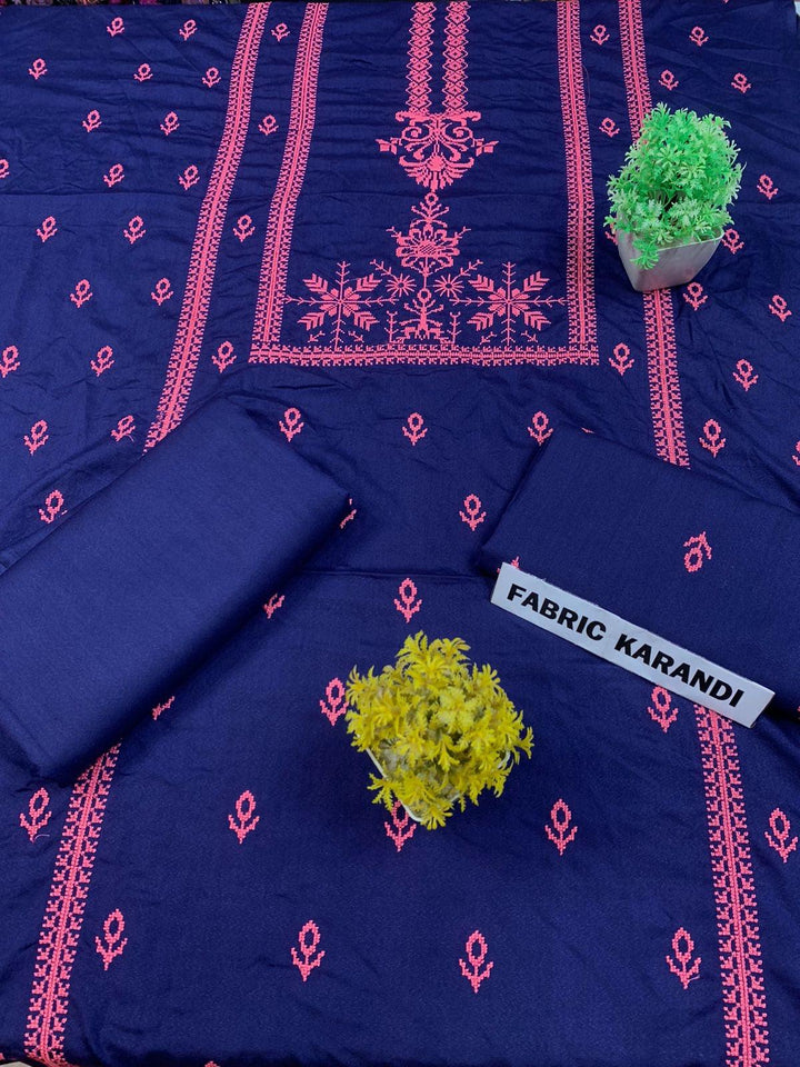 Regal Dusk Bareeze from ESHMEEN showcases beautifully intricate blue patterns on purple fabric, with two artfully folded pieces labeled as part of the Winter Collection. A small yellow bouquet is elegantly placed at the center on this premium quality fabric.