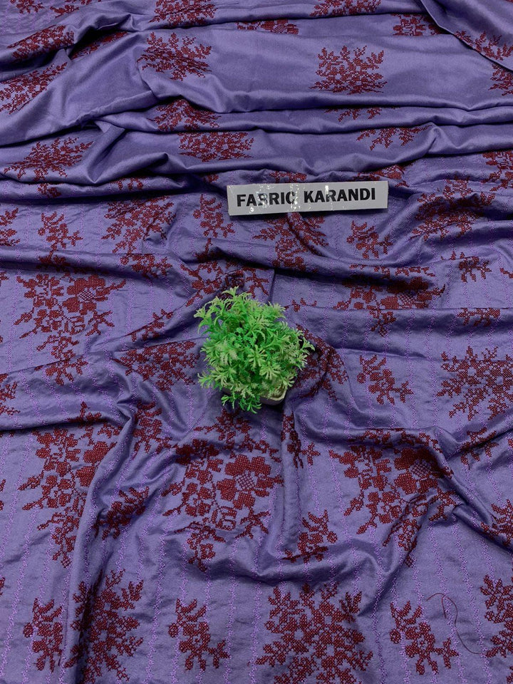 The "Regal Charm Bareeze" from ESHMEEN's Winter Collection showcases a purple fabric adorned with red floral patterns, highlighted by a small green plant in the center. A label at the top indicates it is part of the Premium 3-Piece Fabric Karandi.