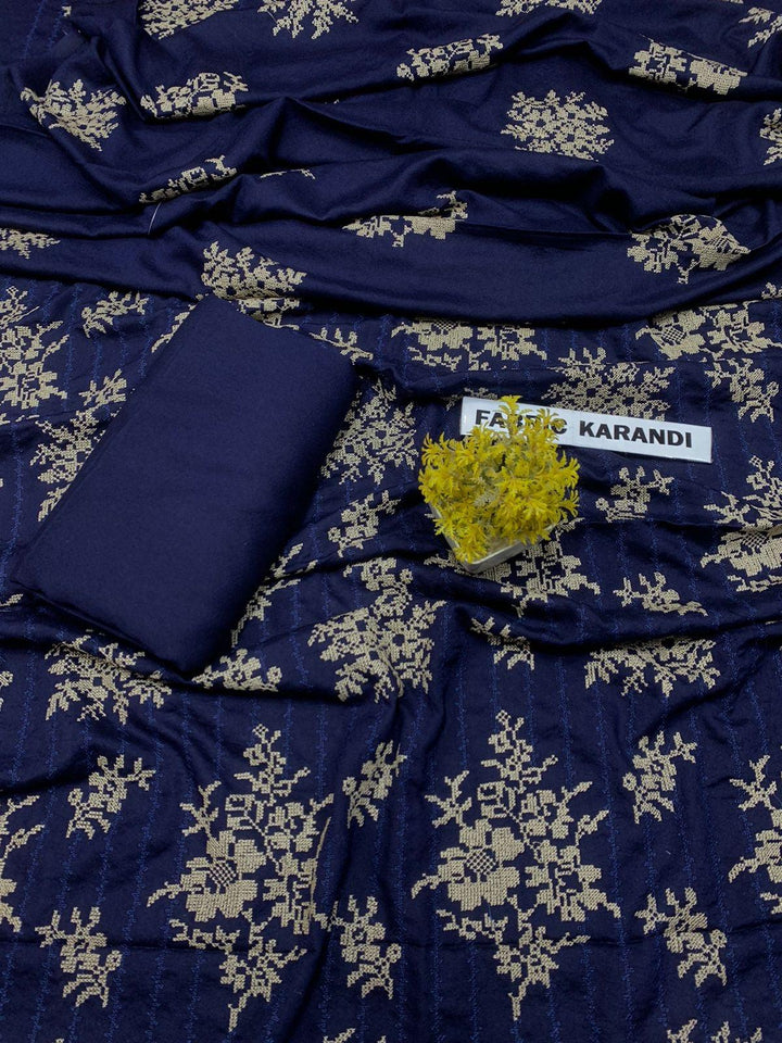 The "Regal Charm Bareeze" from ESHMEEN's Winter Collection showcases a purple fabric adorned with red floral patterns, highlighted by a small green plant in the center. A label at the top indicates it is part of the Premium 3-Piece Fabric Karandi.